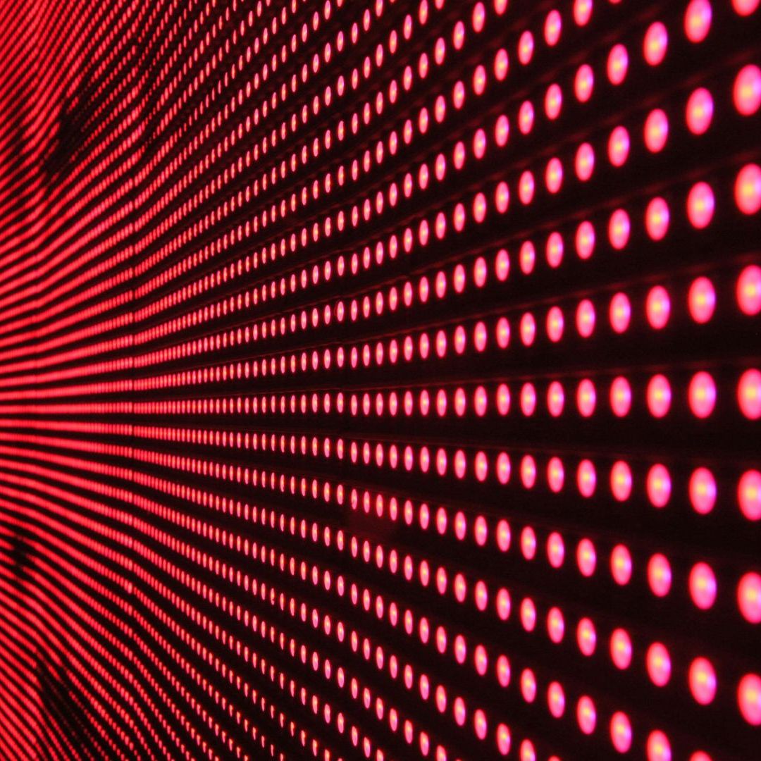 A wall of red dots on a black background. This image is used to represent red light therapy, a hair growth treatment.