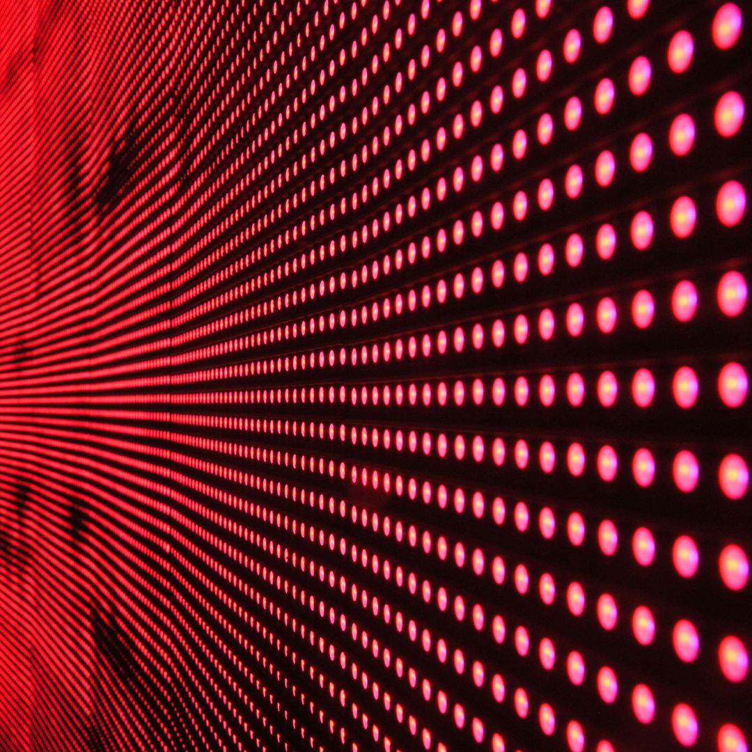 A wall of red dots on a black background. This image is used to represent red light therapy, a hair growth treatment.